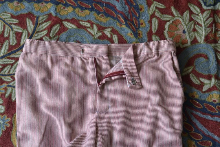 A close-up of the front zip fly on red and white trousers.