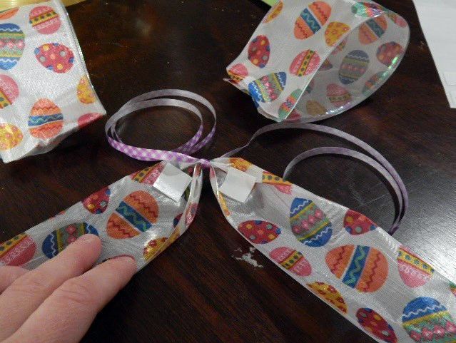 Find the center of the longer piece and tie on some curly ribbon (this is how you will attach the bow to your package). Add a UGluÂ® Dash to the base of each tail of the ribbon.
