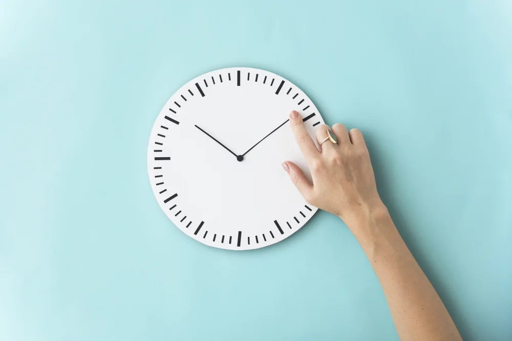A closeup of someone touching the hands of an analog clock.