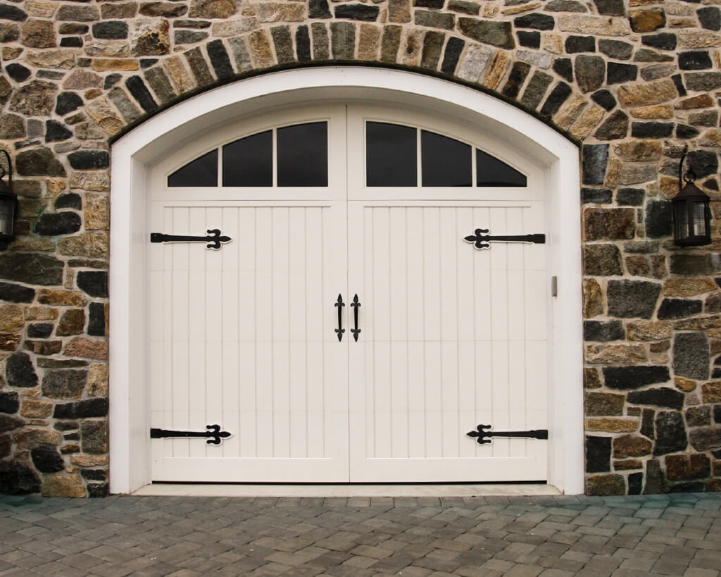 a single white, rounded carriage garage door with windows and decorative hardware.