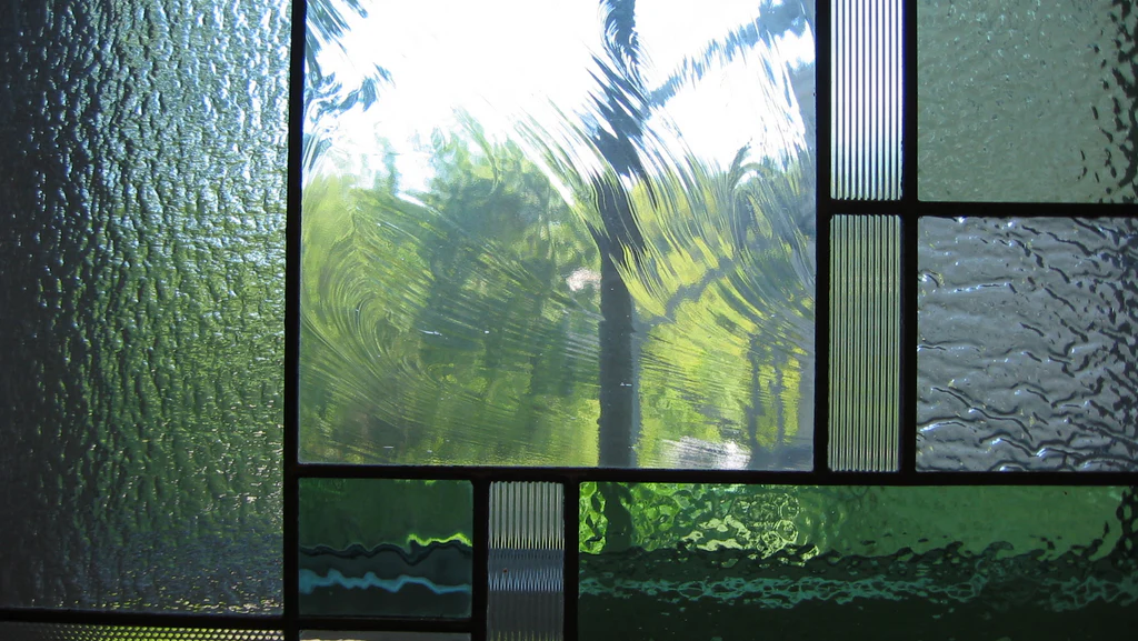 A green stained glass window casting colorful reflections
