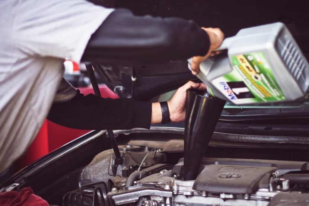 Man pouring oil into car motor