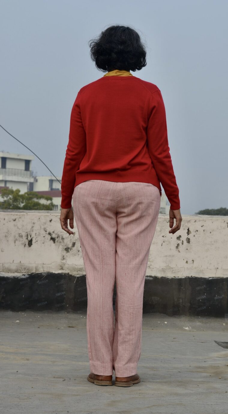 A back view of a woman wearing red and white striped trousers and a red sweater.