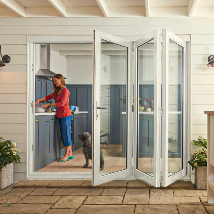 Woman preparing food from kitchen next to open patio bifold door