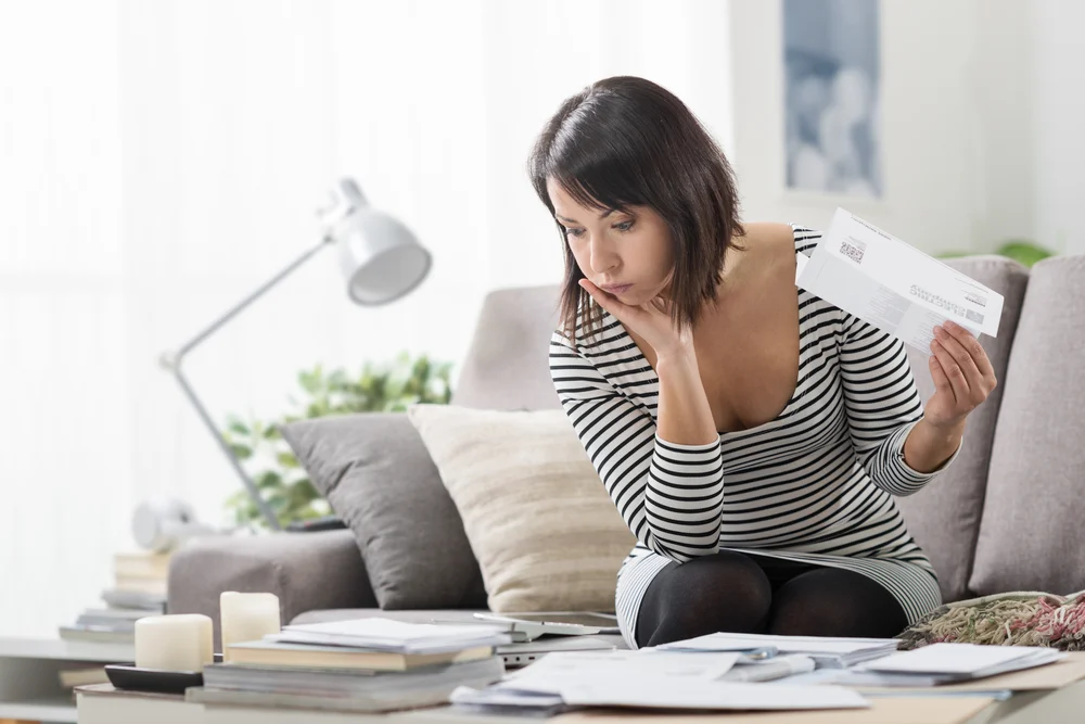 A woman reviewing energy bills in her living room.
