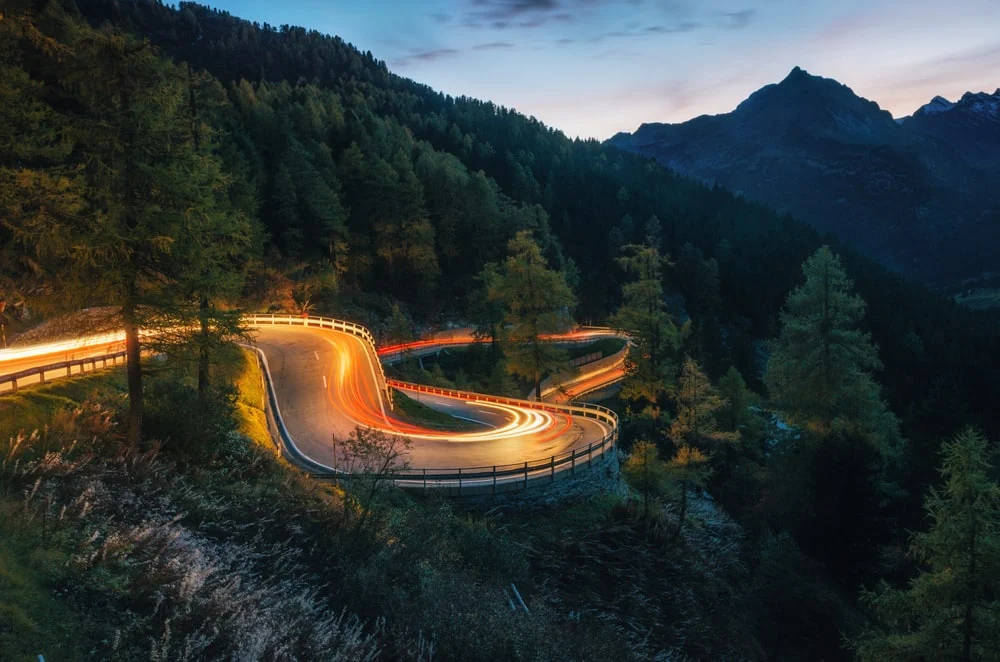 Zooming lights on a winding mountain road at twilight