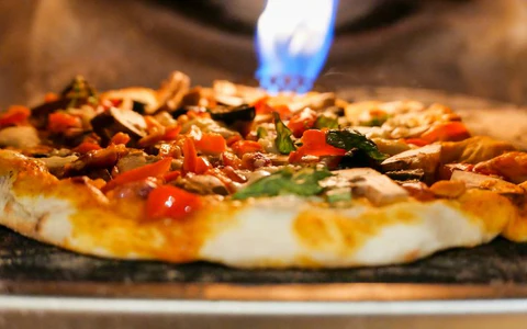 A pizza is being cooked in a wood fired oven.