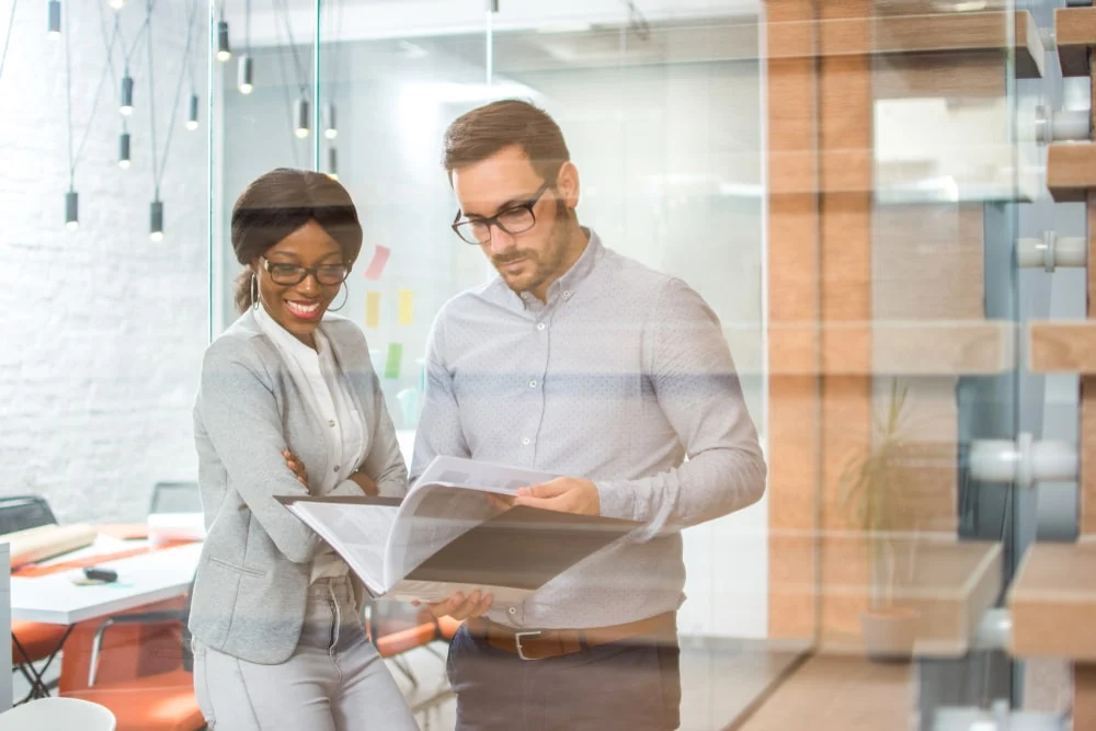 Two colleagues browse through a business plan at the office. 