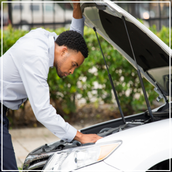 man checking under vehicle hood