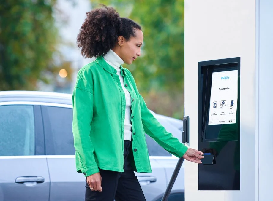 A woman pays for her charging session at the screen of an EVBox Troniq Modular charging station