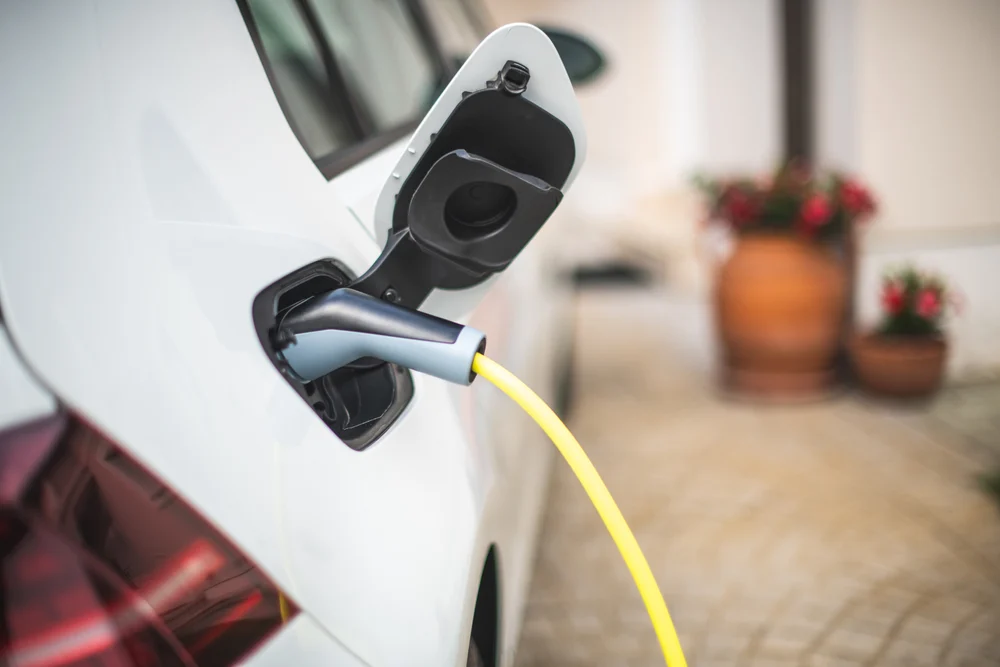 A closeup of an electric car charging in a residential setting.