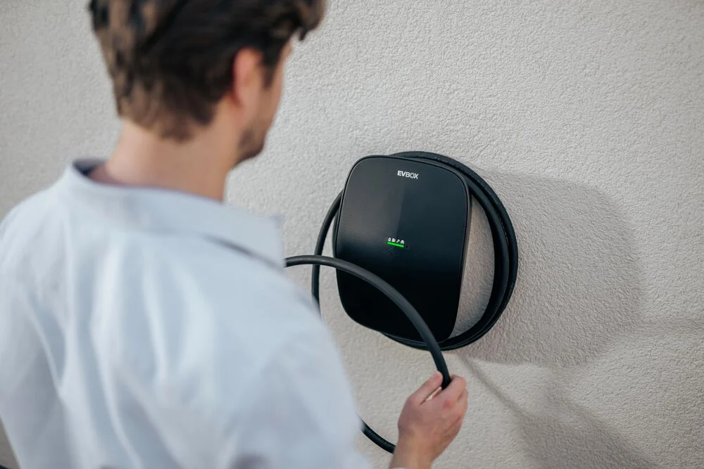Man wrapping charging cable around EVBox Livo charging station.