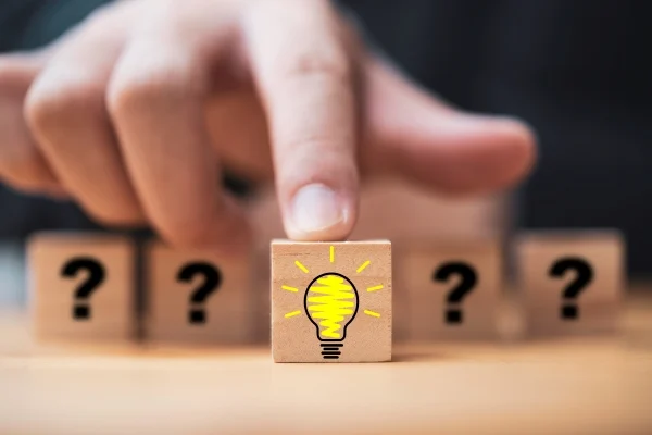 Hand-Pushing Lightbulb Drawing Among Wooden Cube Blocks