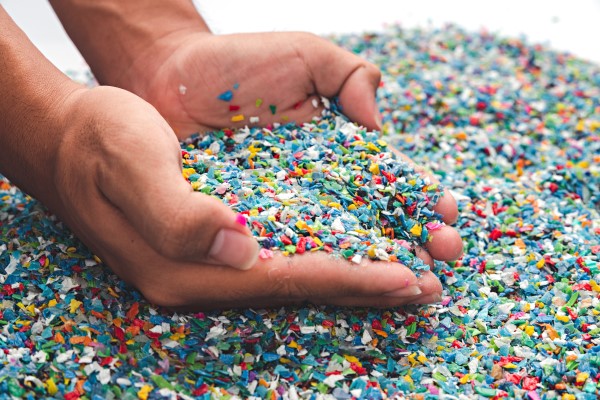 A pair of hands scooping colored plastic pellets in their palm