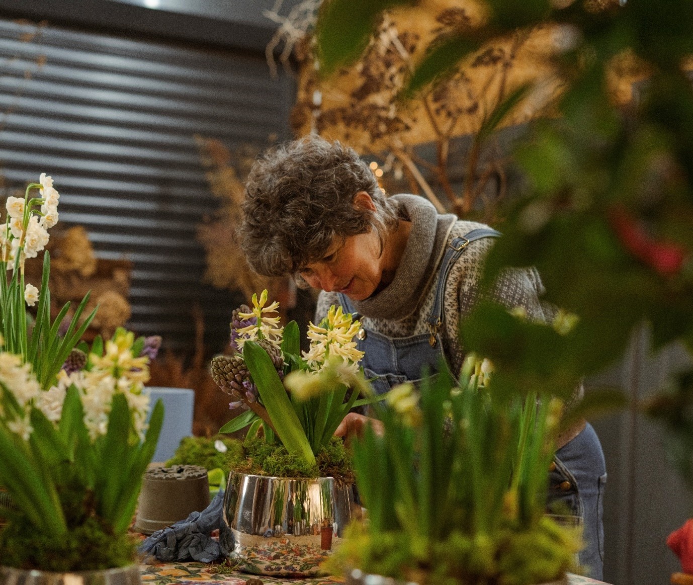 Woman creating flower arrangements in From The Anvil's stainless steel metal plant pots