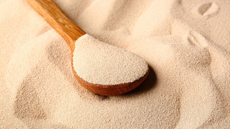 A wooden spoon filled with yeast