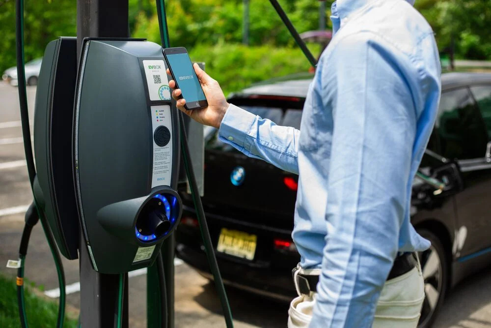 A businessman holding a smartphone to start his EV charging session.
