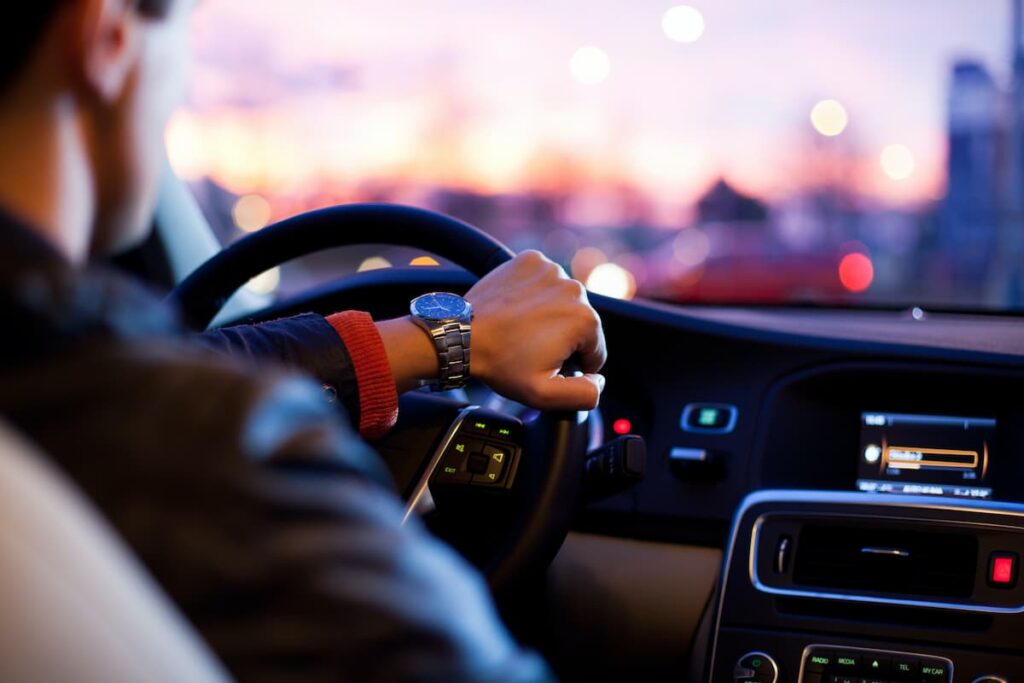 A man driving a connected car during sunset
