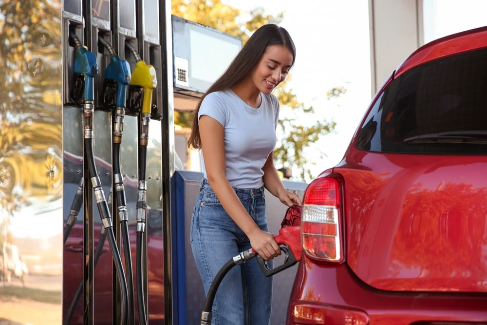 A woman refueling her vehicle at a gas station.