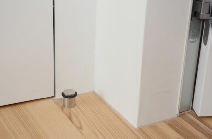 A doorstop on the floor behind a white door