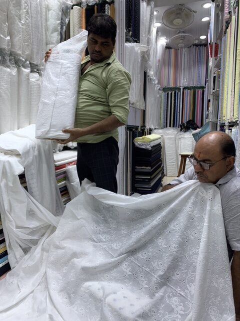 Textile merchants displaying eyelet fabric 