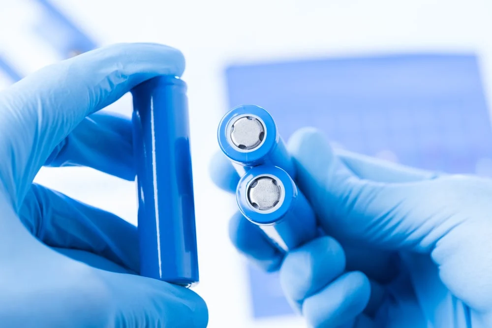 A close up image of Cylindrical cells held by person wearing protective gloves.