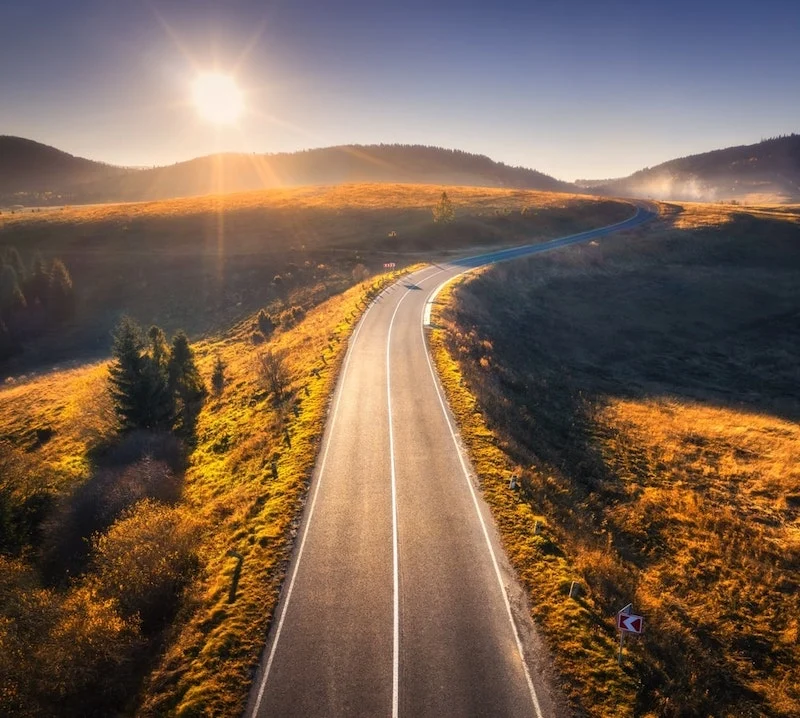 An aerial view of a road in an open area during sunset.