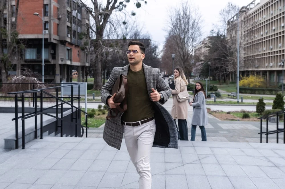 A man in business casual clothes runs on campus