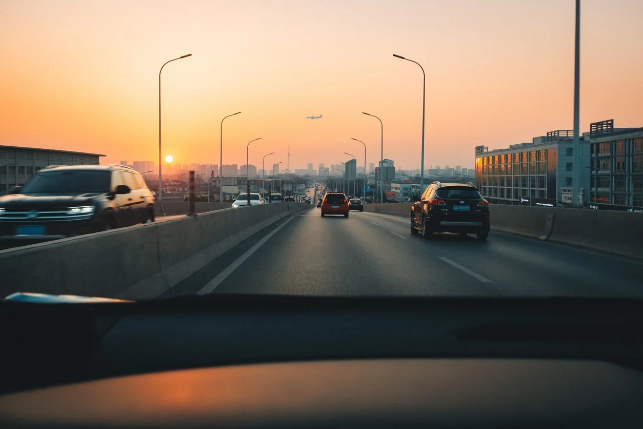 View from inside a car driving down a road with other cars on sight.
