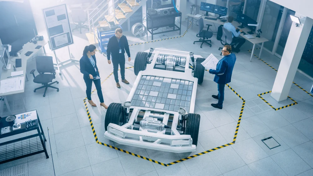 Engineers looking at an EV battery pack that's on a bare electric car.