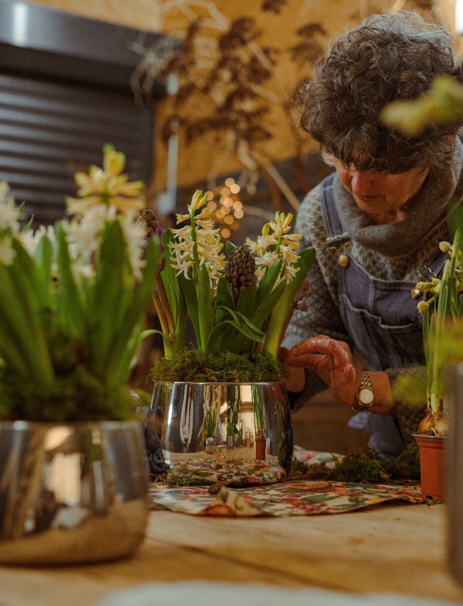 Woman arranging flowers in a Polished Marine Stainless Steel plant pot.