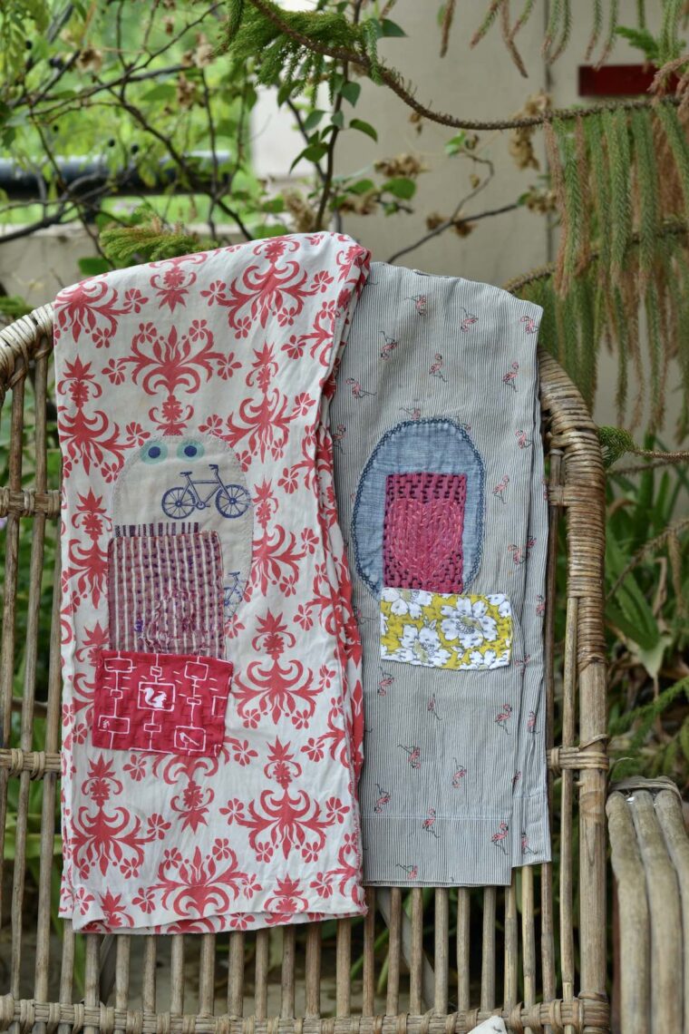 Two pairs of boys pants with visible mending on the knees