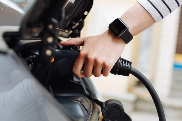 A woman's hand plugging her electric charger to her car.