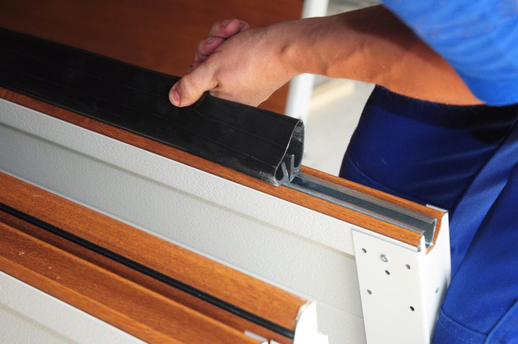 A man installing a new decorative track on a garage door.
