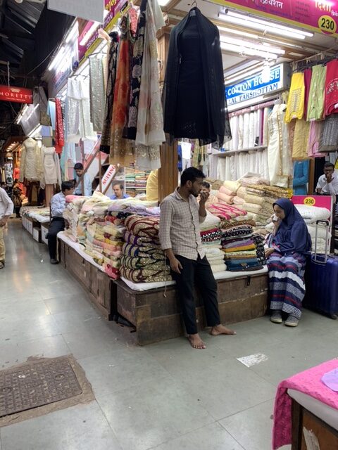 Man and woman talking outside a fabric stall in Mumbai