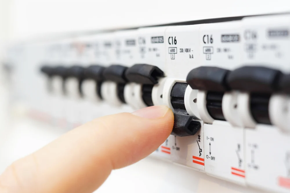 A closeup of a hand switching off the electricity power from a meter box.