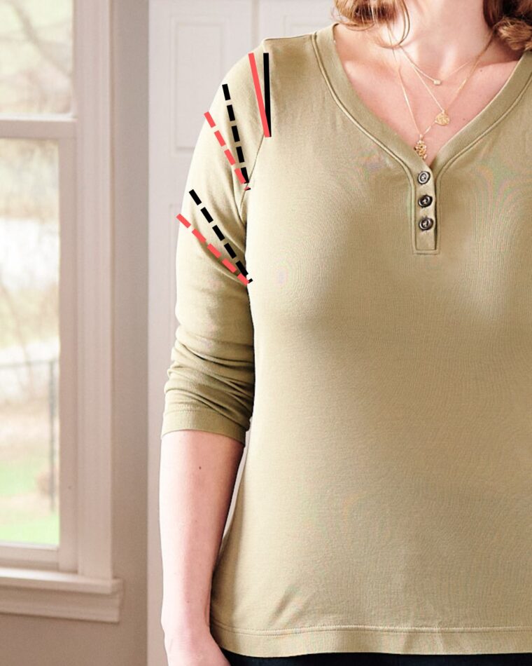 A close-up view of a shirt sleeve showing drag lines. Dashed black lines have been drawn on the sleeve to demonstrate. Red dashed lines have been drawn to demonstrate what happens to the fabric after the adjustment.