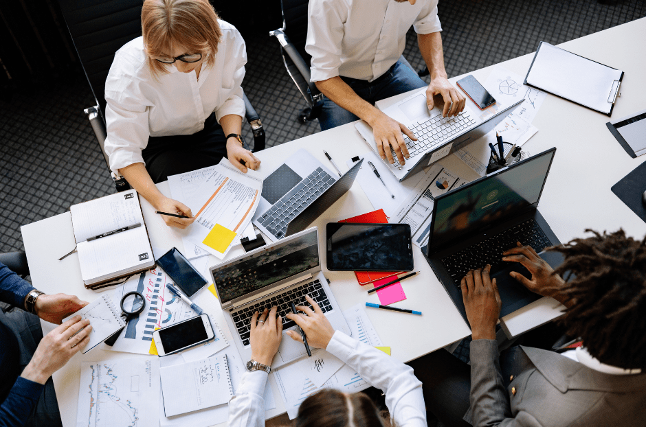 People working in a desk, using papers and laptops.