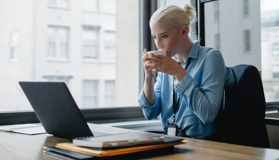 A manager in an office setting, drinking a coffee whilst reading about creating an EV charging business case.