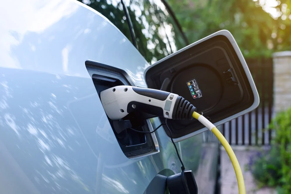 Electric car charger plugged into white car.