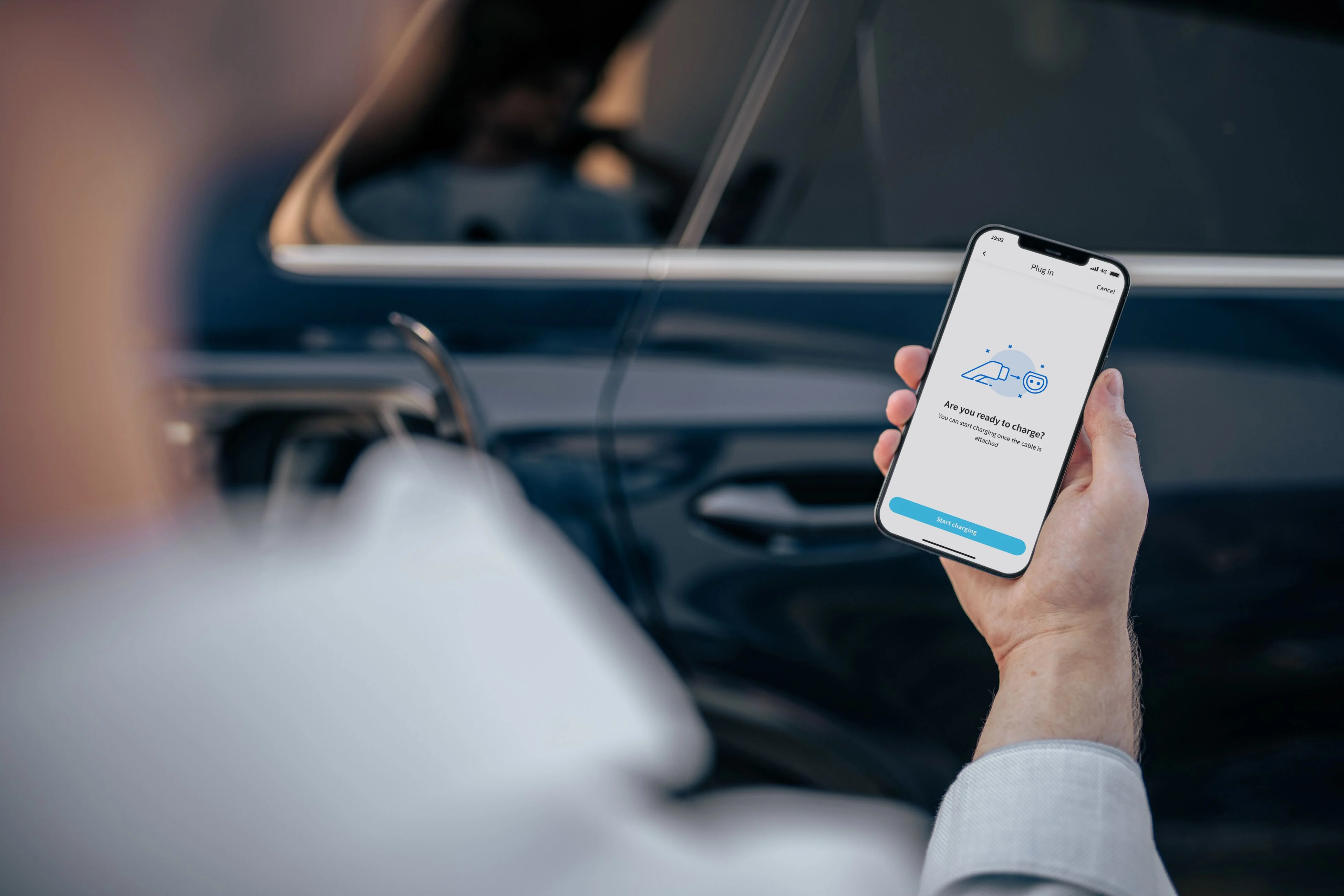 A man looking at his smartphone showing a charging app.