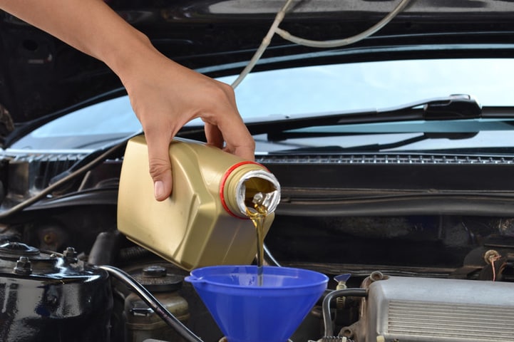 Mechanic pouring oil into funnel during oil change