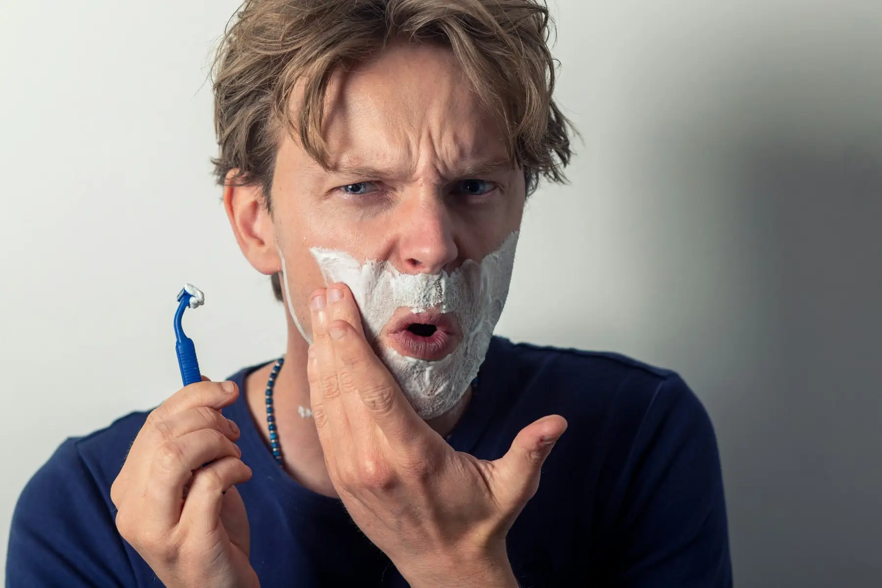 Man struggling to shave in the mirror