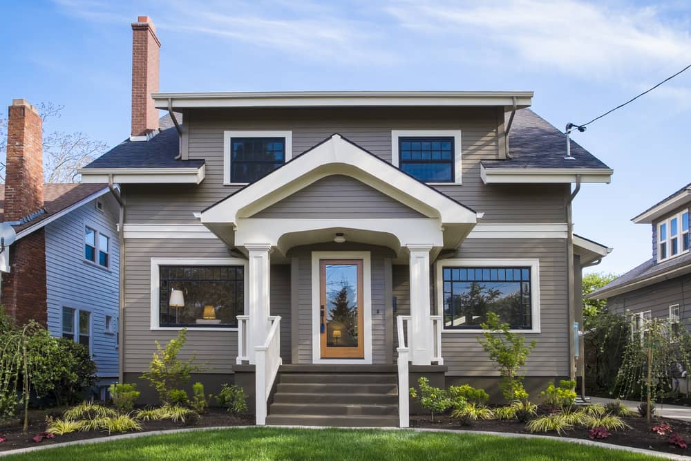 the front view of a home with two symmetrical gardens on either side of the front door.