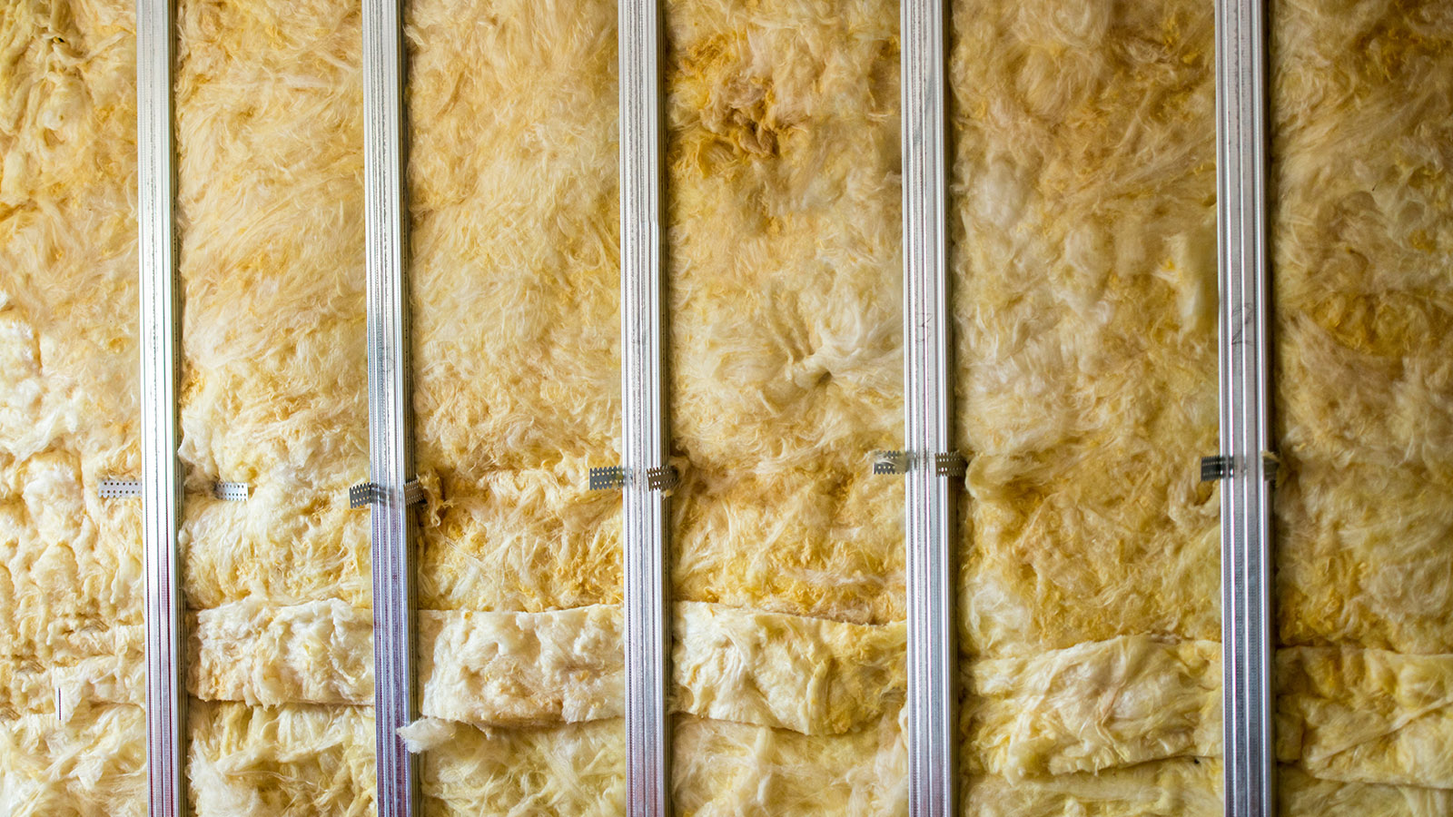 An exposed wall with fresh insulation installed.