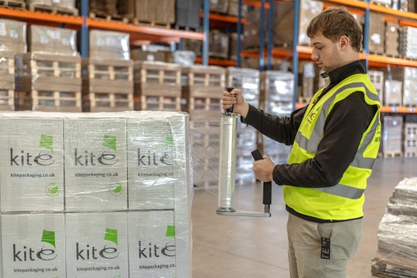 A man in hi-vis hand wrapping a pallet in a warehouse