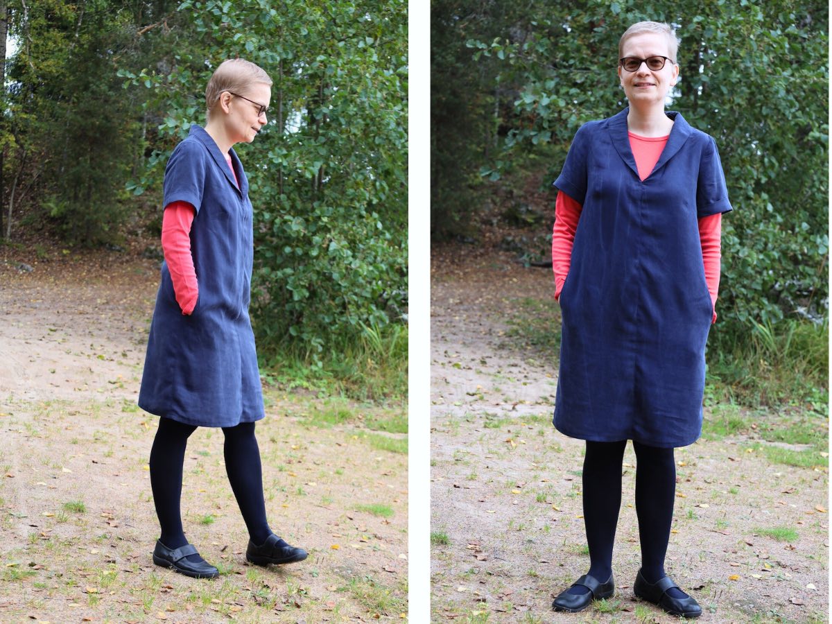 woman with short hair and sunglasses wears a pink long-sleeved t shirt with a navy v-neck, short-sleeved dress on top