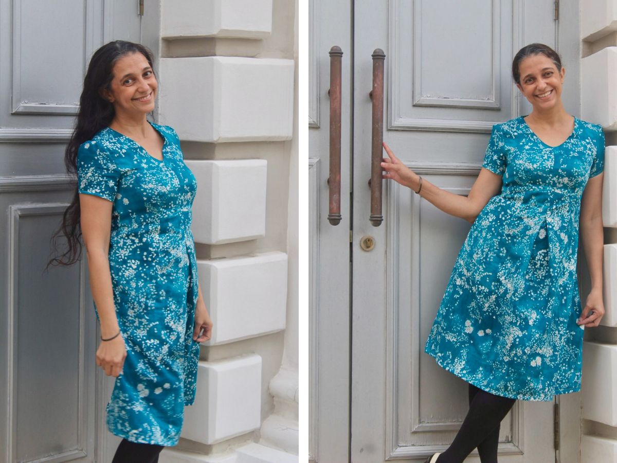 woman stands in a teal short-sleeve, v-neck dress