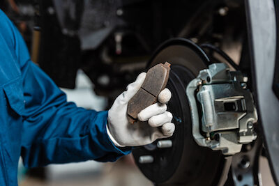 cropped view of mechanic holding brake pad near assembled disc brakes auto mechanic holding a brake pad
