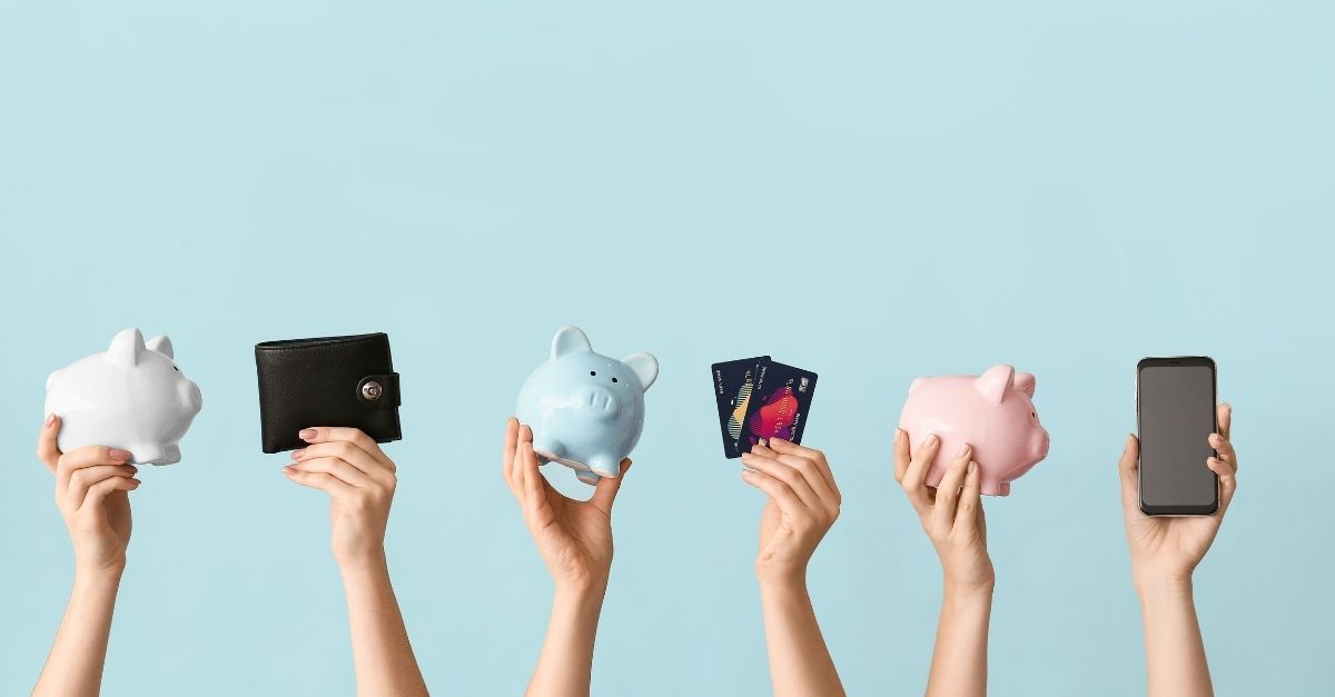 Hands in the air holding piggy banks, credit cards, wallet and a mobile phone
